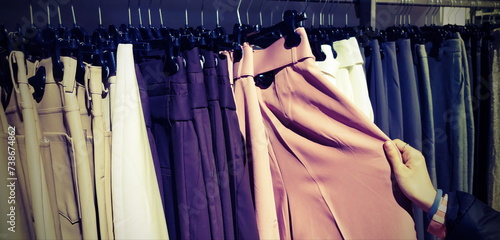 hand of girl choosing trousers in trendy clothes shop with old toned effect photo
