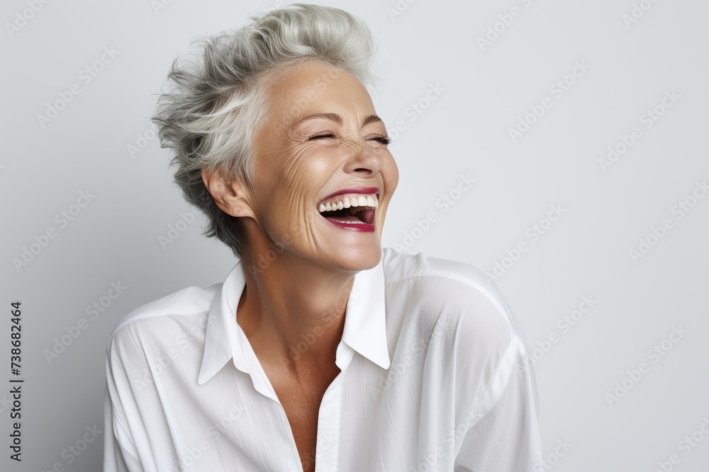 Happy senior woman laughing and looking up. Portrait of beautiful mature woman in white shirt. Happy senior woman laughing and looking up. Portrait of beautiful mature woman in white shirt.