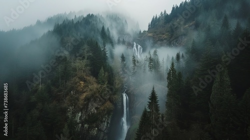 Aeriel view of waterfall between trees of high hills in a foggy day. Water flows down to rocky mountain. © Emil