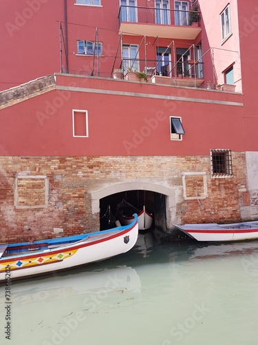 Gondolas on canal and a pink building in Venice
