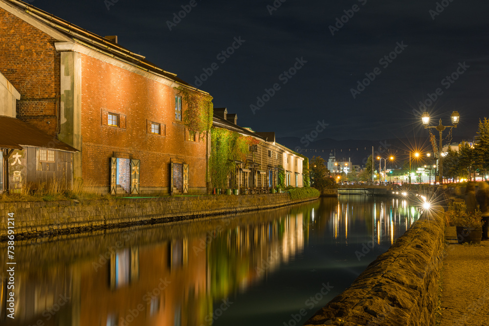 日本　北海道小樽市にある小樽運河沿いのガス灯に明かりが灯った夜景とライトアップされた石造倉庫群