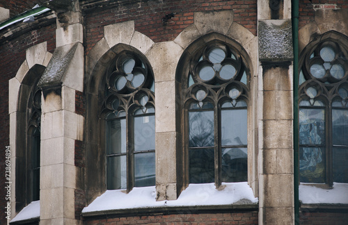 Three old pointed gothic windows with stained glass on facade of the building. Baroque and Gothic architecture. Church of St. Olga and Elizabeth. Lviv, Ukraine.
