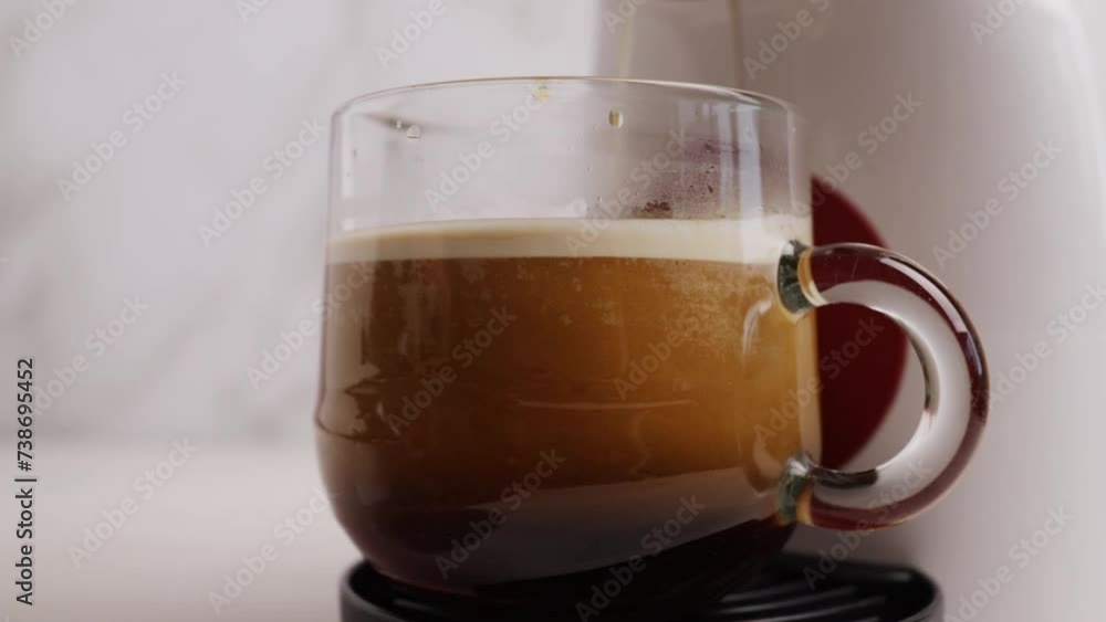 Coffee is poured into a cup from a capsule coffee machine, lungo preparation, closeup, aromatic hot beverage