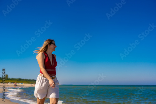 Fototapeta Naklejka Na Ścianę i Meble -  Beautiful mid adult woman walking on sunny beach
