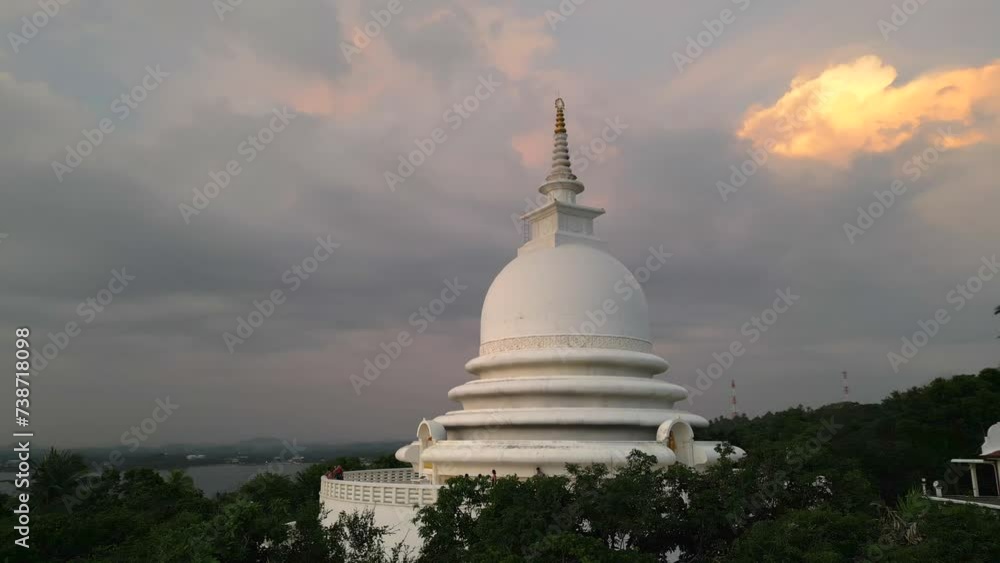 White pagoda buddhist temple among the jungle against the sunset clouds. Japanese Peace Pagoda in Sri Lanka aerial view. White pagoda buddhist temple among the jungle against the sunset clouds. Japanese Peace Pagoda in Sri Lanka aerial view.