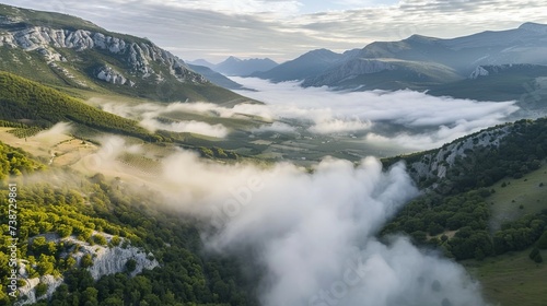 Aerial view of a valley with fog in early morning mist among mountains in Psaka, Epirus, Greece. © Emil