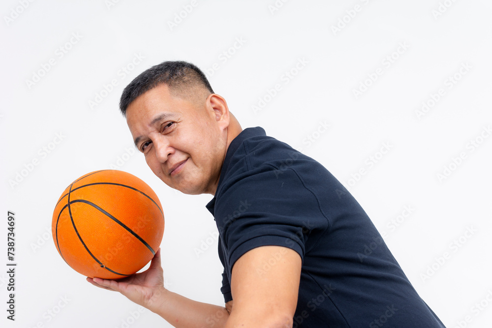A skilled middle aged man smiling while holding a basketball in a defensive stance. Dressed in a casual polo shirt.