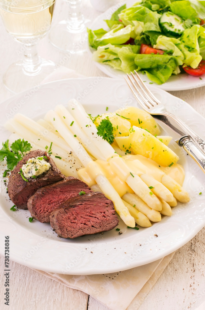 Traditional roasted angus beef steak with with white asparagus, boild potatoes and fresh salad served as close-up on a classic plate