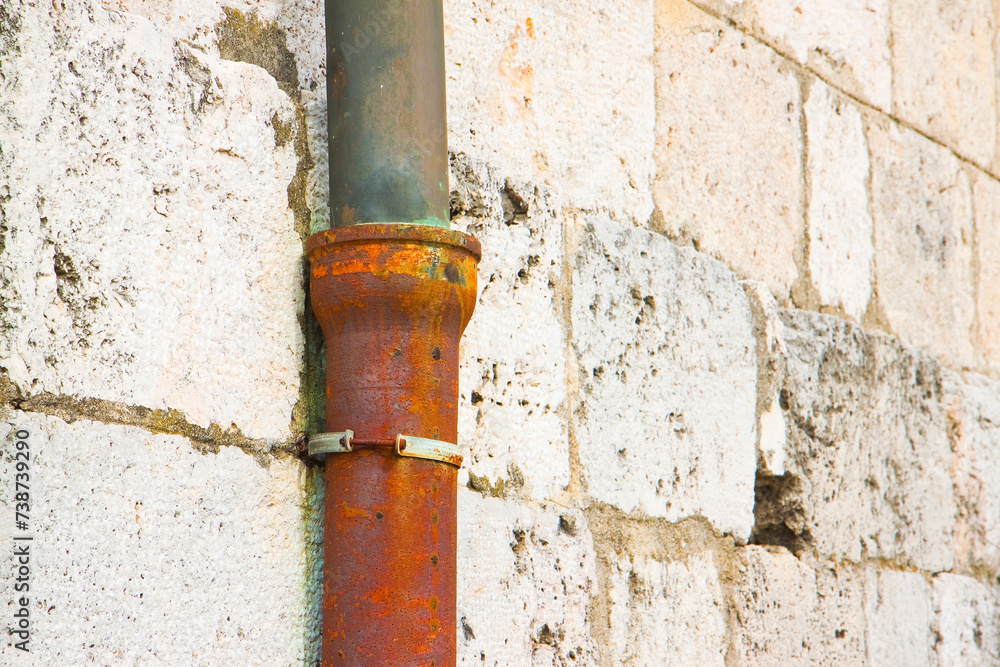 Old cast iron and copper downpipe against a stone wall - (Italy) Old cast iron and copper downpipe against a stone wall - (Italy)