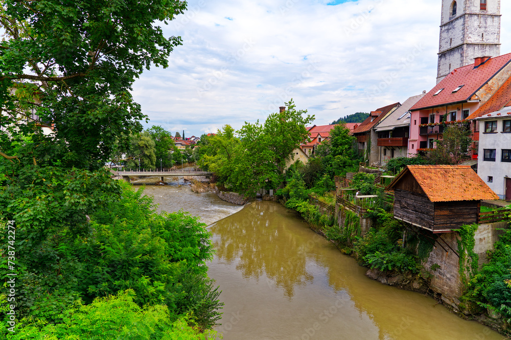 Old town with historic houses and Selska Sora River at City of Skofja Loka on a cloudy summer day. Photo taken August 9th, 2023, Škofja Loka, Slovenia.