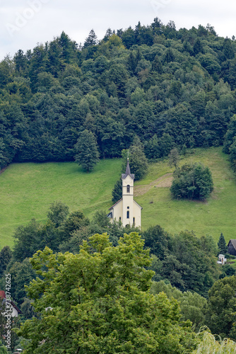 Holy Cross Church at Pustal settlement on a hill at municipality of Slovenian City of Skofja Loka on a cloudy summer day. Photo taken August 9th, 2023, Škofja Loka, Slovenia.