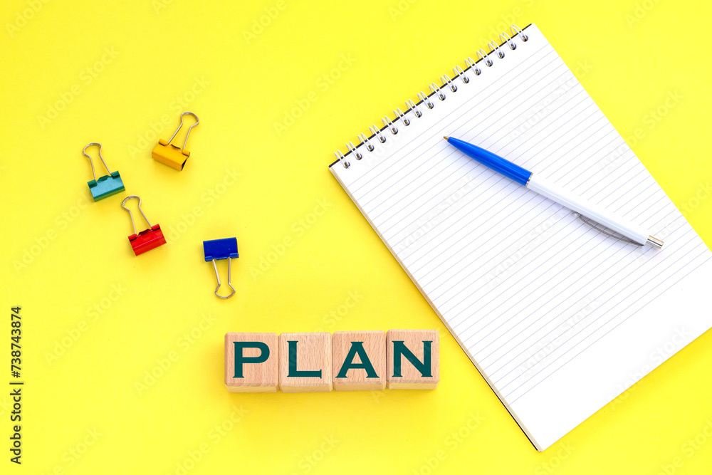 Notepad and pen on the background. Wooden cubes with word plan. Notepad and pen on the background. Wooden cubes with word plan.