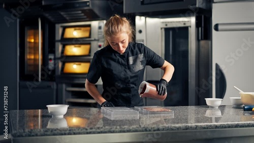 Chocolatier pours melted hot chocolate into a transparent chocolate mold for making natural sweets in confectionery shop