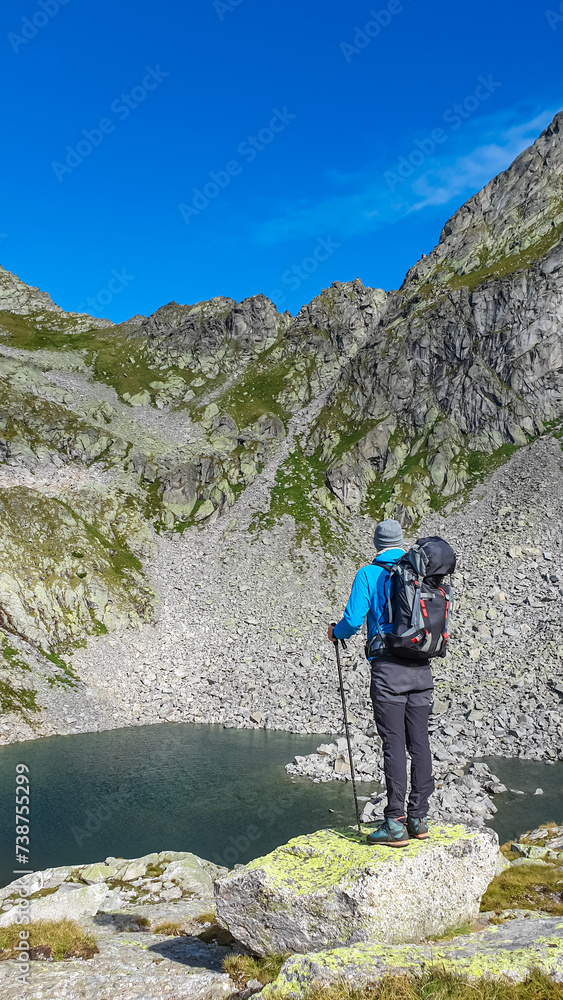 Hiker man at alpine lake Grünecker See with panoramic view of majestic mount Roemerspitz in High Tauern National Park, Carinthia, Austria. Idyllic hiking trail in Austrian Alps. Hike paradise Mallnitz