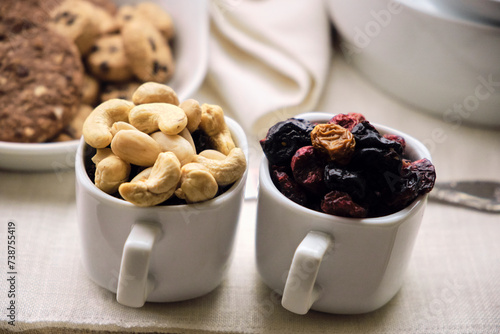 Dried fruit and red fruits in cups, whole grain cookies with chocolate complete the tray. Close-up. photo