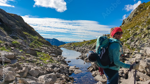 Obraz na płótnie Hiker woman crossing a small river in High Tauern National Park, Carinthia, Austria. Idyllic hiking trail from Hannoverhaus to Hagener cottage in Austrian Alps. Hike paradise Mallnitz. Wanderlust w salonie