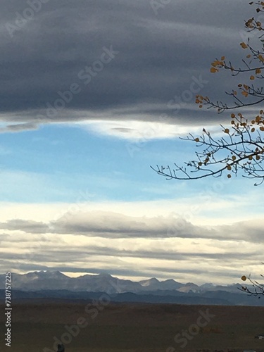 The rolling prairie of Longview Alberta topped with the grey solitude of a Chinook cloud formation with the silhouette of a tree in the foreground. 
 photo