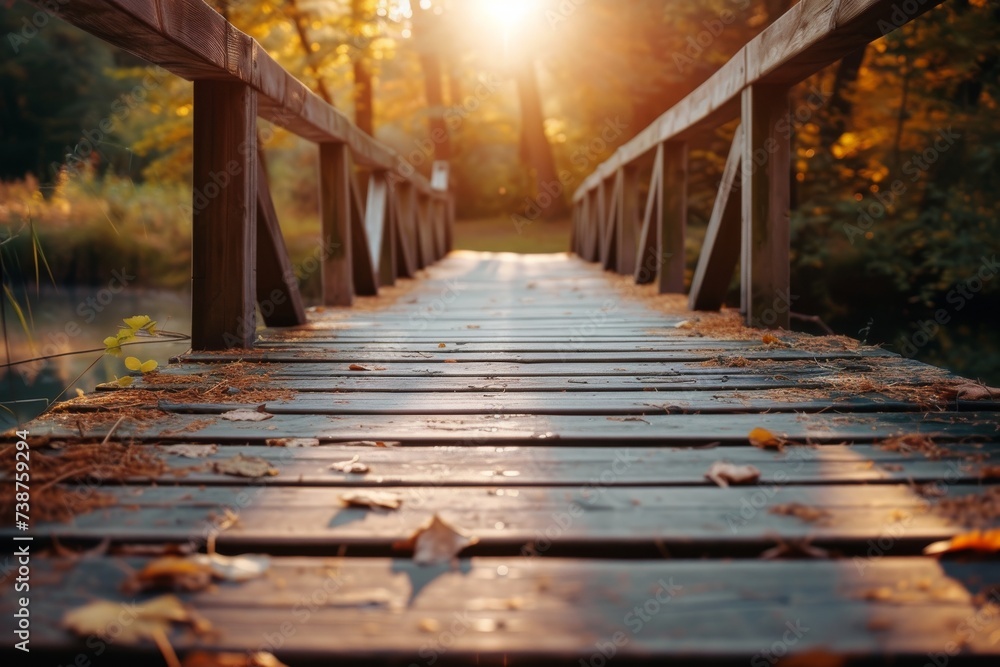 Obraz premium As the autumn sun sets, its golden light filters through the trees and illuminates the wooden bridge, inviting us to cross over and explore the natural beauty of the outdoor world