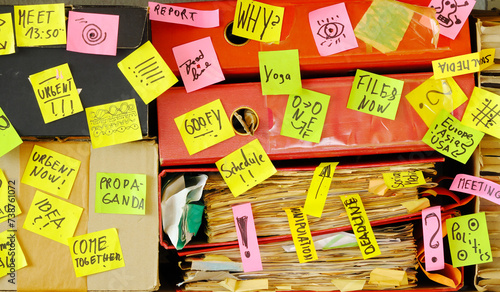Messy file folder,sticky notes and old papers.Red tape, bureaucracy,overworked,mental burnout,exploitation,messy office and chaotic business concept.