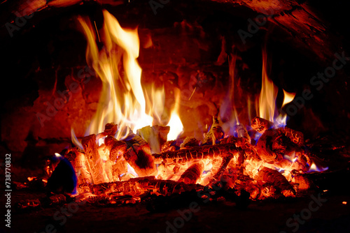 The fire crackles as wood is consumed, emitting light and warmth.