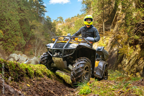 Fototapeta Naklejka Na Ścianę i Meble -  Man on quad bike. Racer rides off-road. Quad bike for racing in mountainous areas. ATV driver looks around. Man takes part in ATV racing. Guy with quad bike in picturesque nature. Extreme trip