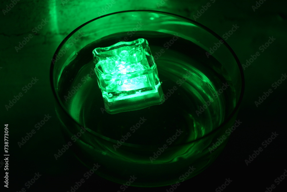 Beautiful, stylish photo of parties, celebrations, one glass champagne glass with glowing plastic ice cubes in drinks that glow green light. Beautiful, stylish photo of parties, celebrations, one glass champagne glass with glowing plastic ice cubes in drinks that glow green light.