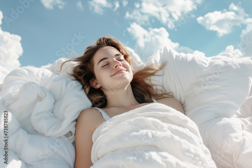 a beautuful young woman with a smile sleeps on a bed with a soft white dazzling blanket and pillows