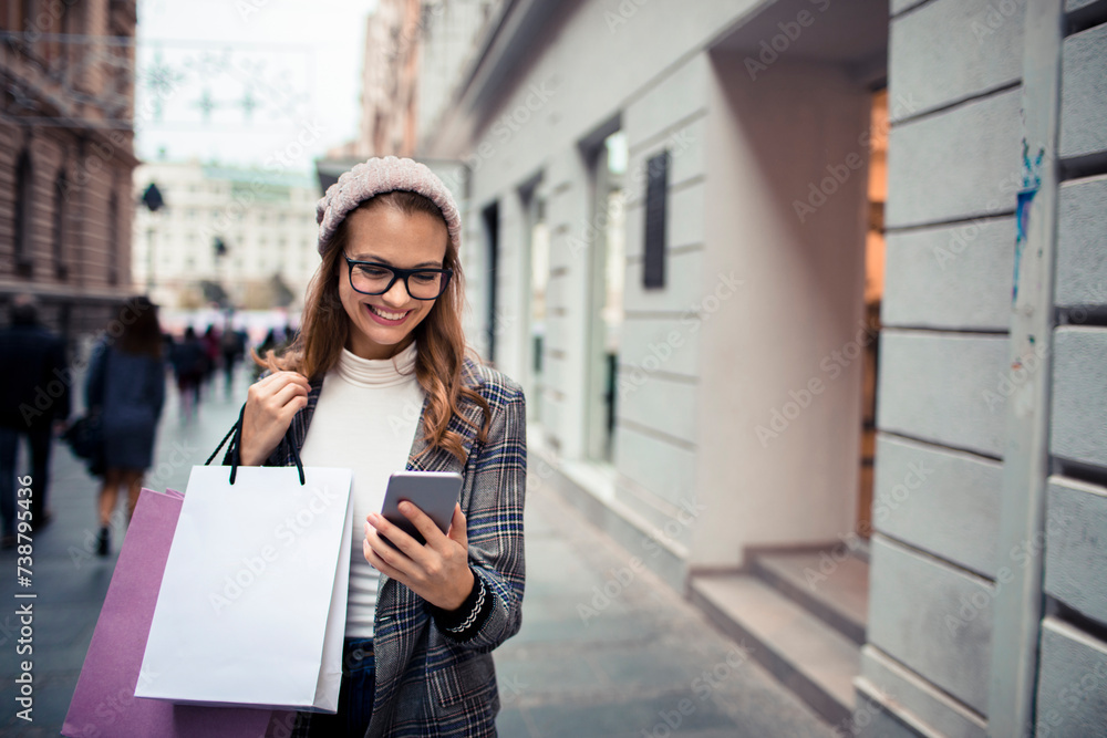 Young stylish woman using smartphone while shopping in city Young stylish woman using smartphone while shopping in city