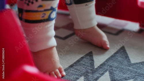 Baby boy's feet standing on the floor in a walker