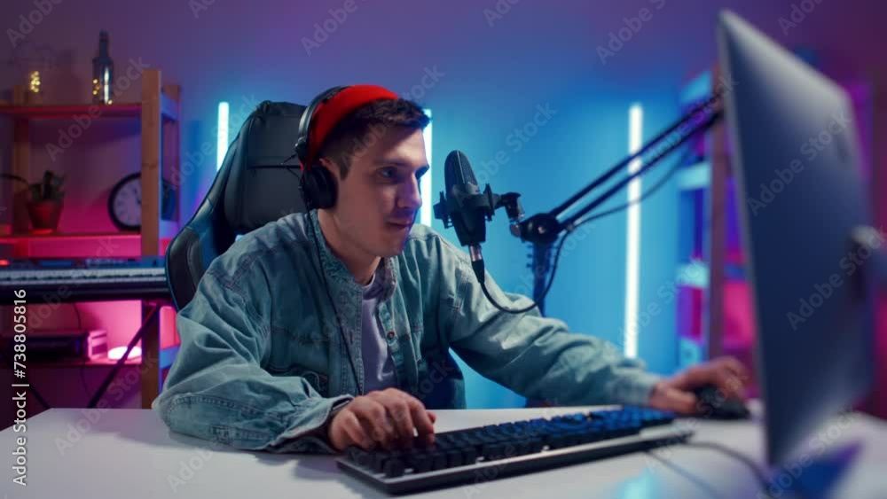 Young hipster man playing online computer video game, colorful lighting broadcast streaming live home. Ecstatic celebration winning match. Gamer lifestyle, E-Sport online gaming technology concept Young hipster man playing online computer video game, colorful lighting broadcast streaming live home. Ecstatic celebration winning match. Gamer lifestyle, E-Sport online gaming technology concept