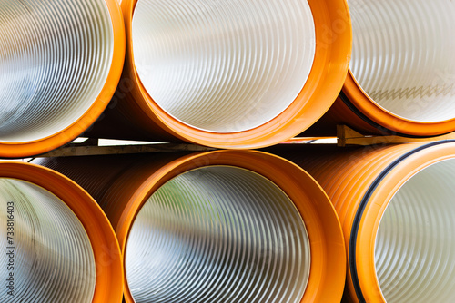 Fotografia Large diameter pipes lie on the ground against the backdrop of a multi-storey residential building
