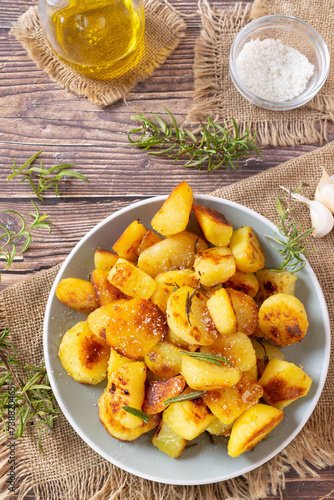 Classic Italian roasted potatoes, roast potato recipe, baked potatoes with rosemary on a wooden table