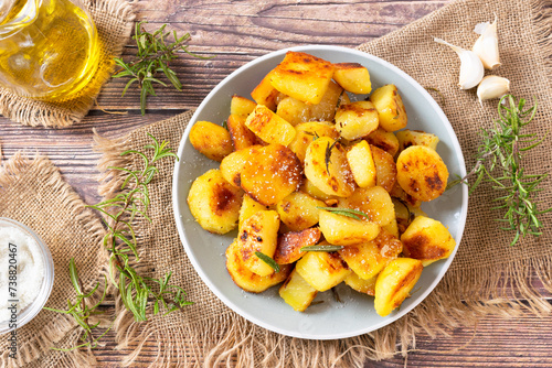 Classic Italian roasted potatoes, roast potato recipe, baked potatoes with rosemary on a wooden table