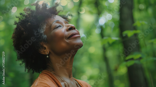 relaxed Mature Black American woman breathing fresh air in a green forest