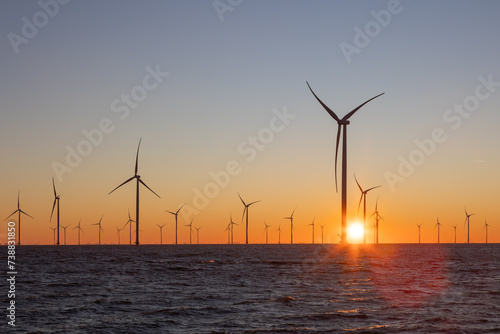 Off shore wind turbines or high, tall wind mills at sea during sunrise  © Thomas