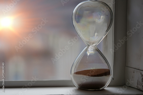 Sunrise through a window with a hourglass with flowing sands