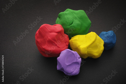 Colorful plasticine balls lying on a black surface. Close up.