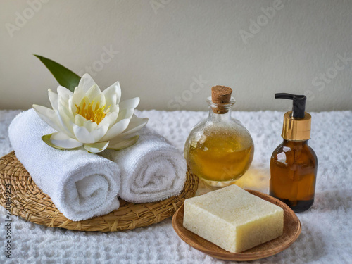 Gua sha facial stone, cosmetic bottles, towels and candle on wooden background still life stock photo images. Spa and wellness setting with massage stone. Beauty spa treatment composition images