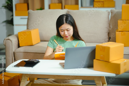 young Asian entrepreneur, the owner of a small clothing store, organizes online live streams showcasing products packaged in cardboard boxes, ensuring prompt and efficient delivery.
