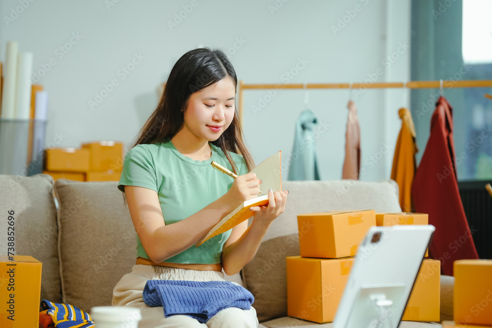 young Asian entrepreneur, the owner of a small clothing store, organizes online live streams showcasing products packaged in cardboard boxes, ensuring prompt and efficient delivery. young Asian entrepreneur, the owner of a small clothing store, organizes online live streams showcasing products packaged in cardboard boxes, ensuring prompt and efficient delivery.