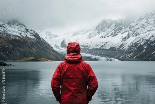 Man in Red Jacket Overlooking Snowy Mountains by a Lake
