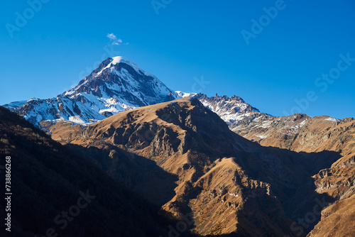 Majestic snow-capped peaks reaching for the sky, surrounded by the serene beauty of pure blue skies.