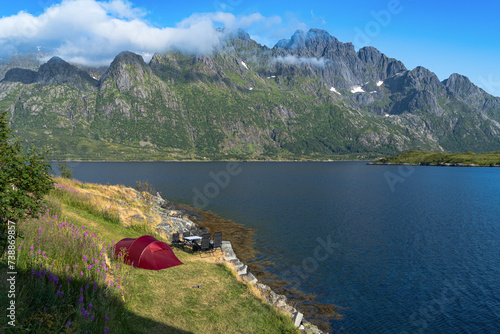 Red tent and the campsite on the fjord shore at Lofoten island With high mountains on the background in Norway