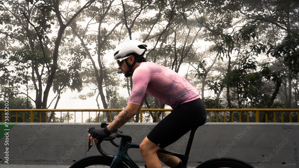 male cyclist in side view riding a bike on a famous hill in colombia on a cold, foggy day