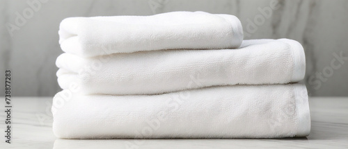 Neatly folded white towels stacked on a surface with a clean and modern aesthetic. photo