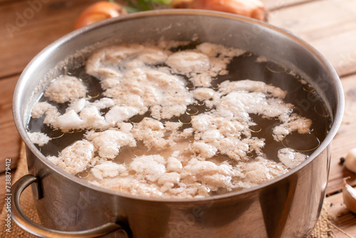 Foto Removing the white foam know as chicken scum from the surface of stock pot when boiling chicken