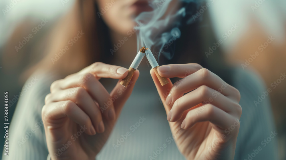 Obraz premium close-up of a person breaking a cigarette in half, with smoke rising from the broken ends, indicating a concept of quitting smoking.