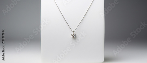 A sleek pendant necklace with a minimalist design, displayed on a soft gray background. photo