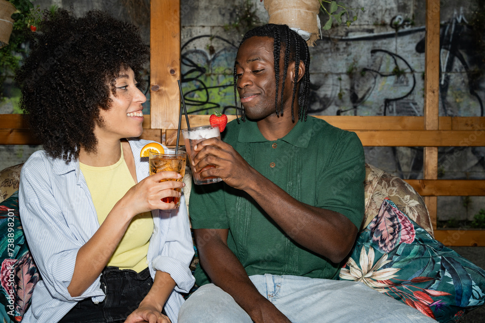 joyful young couple laughing and enjoying cocktails on a rustic café patio, evoking togetherness