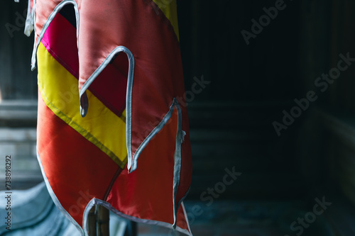 A colorfully striped Buddhist flag hangs low on a calm day at a remote buddhist temple in Vietnam